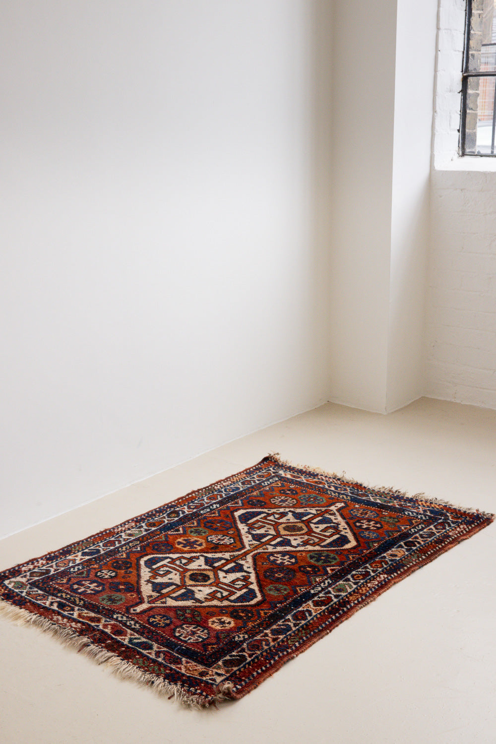 Gigi features a striking central diamond medallion, a classic motif in Qashqai weaving, framed by a repeating floral and gul pattern and a boteh patterned boarder.
