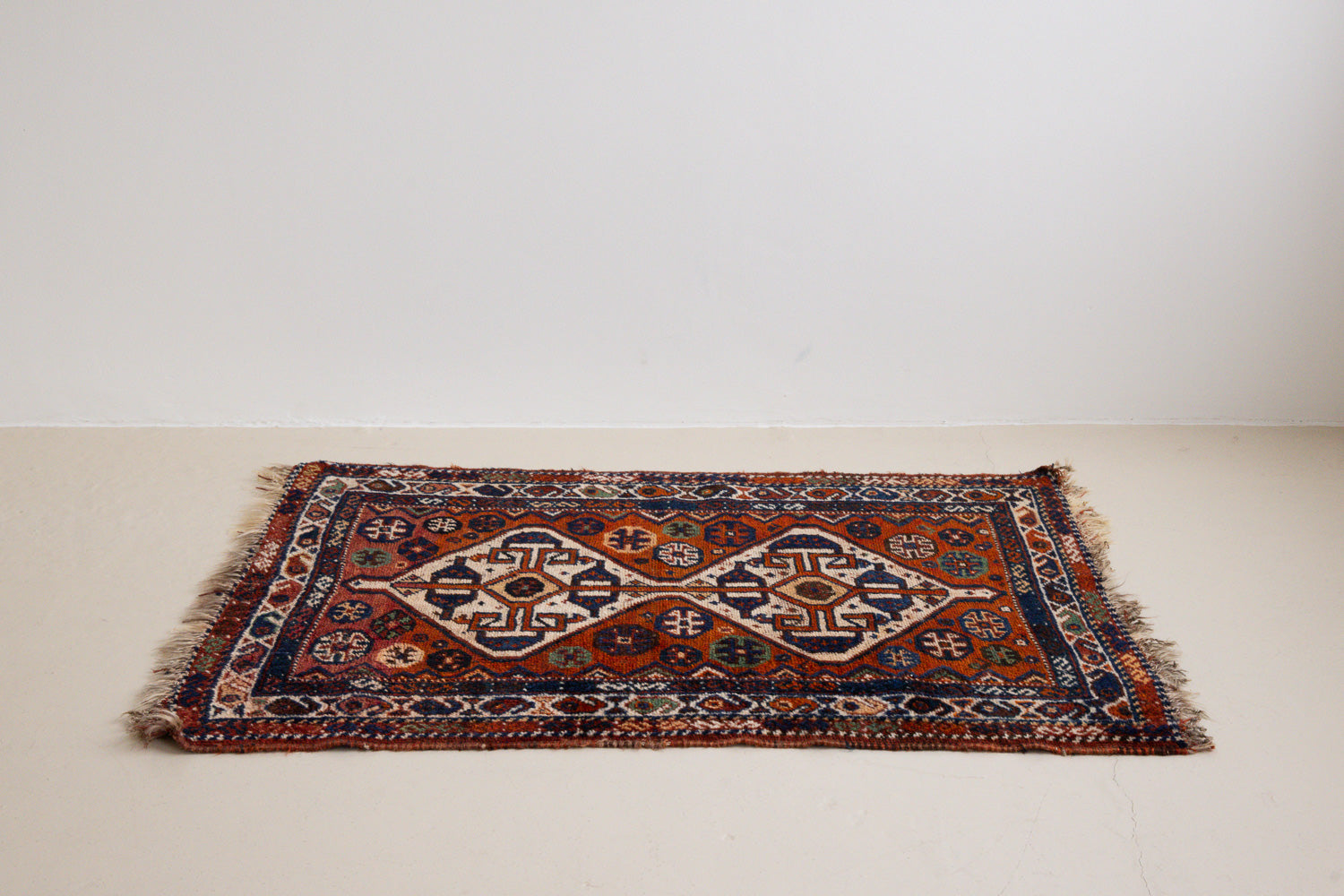 Gigi features a striking central diamond medallion, a classic motif in Qashqai weaving, framed by a repeating floral and gul pattern and a boteh patterned boarder.