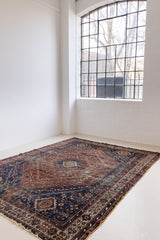 A Qashqai carpet. Sydney features a striking central diamond medallion, a classic motif in Qashqai weaving, framed by a repeating floral, boteh and gul pattern.