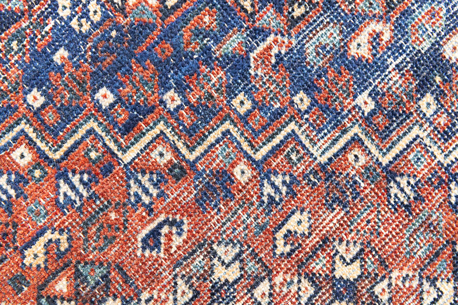 A Qashqai carpet. Sydney features a striking central diamond medallion, a classic motif in Qashqai weaving, framed by a repeating floral, boteh and gul pattern.