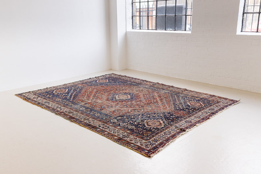 A Qashqai carpet. Sydney features a striking central diamond medallion, a classic motif in Qashqai weaving, framed by a repeating floral, boteh and gul pattern.