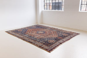 A Qashqai carpet. Sydney features a striking central diamond medallion, a classic motif in Qashqai weaving, framed by a repeating floral, boteh and gul pattern.