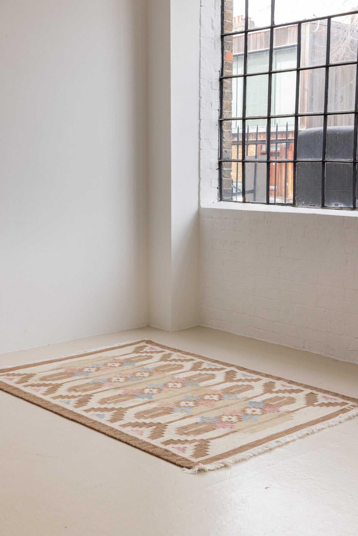 Maja is an original röllakan rug handwoven by the internationally renowned textile designer Ingegerd Silow. This vintage rug features geometric designs in brown, beige, pink and blue on a light beige ground.
