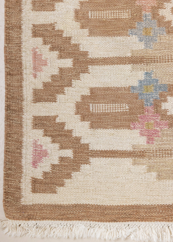 Maja is an original röllakan rug handwoven by the internationally renowned textile designer Ingegerd Silow. This vintage rug features geometric designs in brown, beige, pink and blue on a light beige ground.