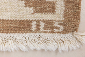 Maja is an original röllakan rug handwoven by the internationally renowned textile designer Ingegerd Silow. This vintage rug features geometric designs in brown, beige, pink and blue on a light beige ground.