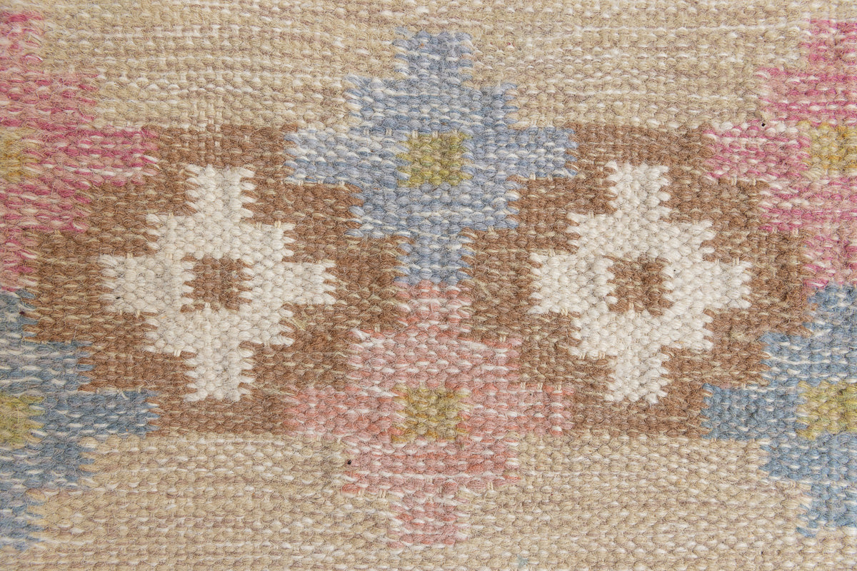 Maja is an original röllakan rug handwoven by the internationally renowned textile designer Ingegerd Silow. This vintage rug features geometric designs in brown, beige, pink and blue on a light beige ground.