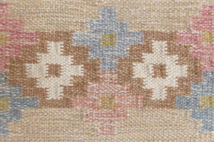 Maja is an original röllakan rug handwoven by the internationally renowned textile designer Ingegerd Silow. This vintage rug features geometric designs in brown, beige, pink and blue on a light beige ground.