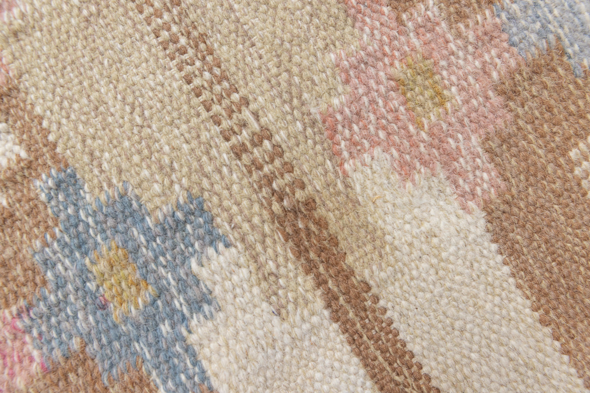 Maja is an original röllakan rug handwoven by the internationally renowned textile designer Ingegerd Silow. This vintage rug features geometric designs in brown, beige, pink and blue on a light beige ground.