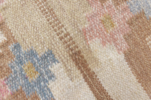 Maja is an original röllakan rug handwoven by the internationally renowned textile designer Ingegerd Silow. This vintage rug features geometric designs in brown, beige, pink and blue on a light beige ground.