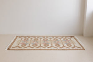 Maja is an original röllakan rug handwoven by the internationally renowned textile designer Ingegerd Silow. This vintage rug features geometric designs in brown, beige, pink and blue on a light beige ground.