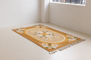 Kaia is a signed vintage Swedish flatweave rug by Ingegerd Silow, featuring a warm ochre field centred framed by stylised florals