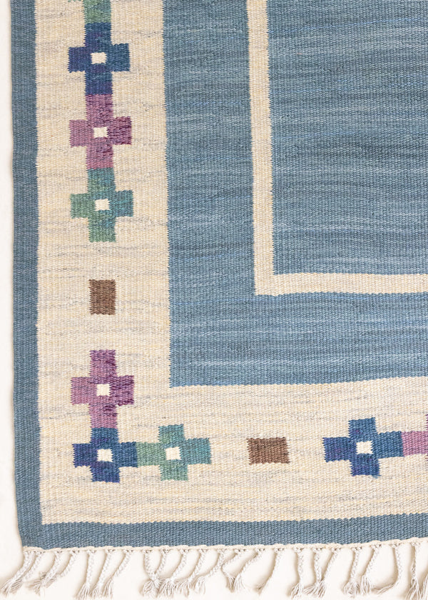 Lumi is a signed vintage Swedish flatweave rug by Anna-Greta Sjöqvist, featuring a calm blue field framed by ivory borders and delicate geometric motifs. Handwoven in wool using the traditional rölakan technique.