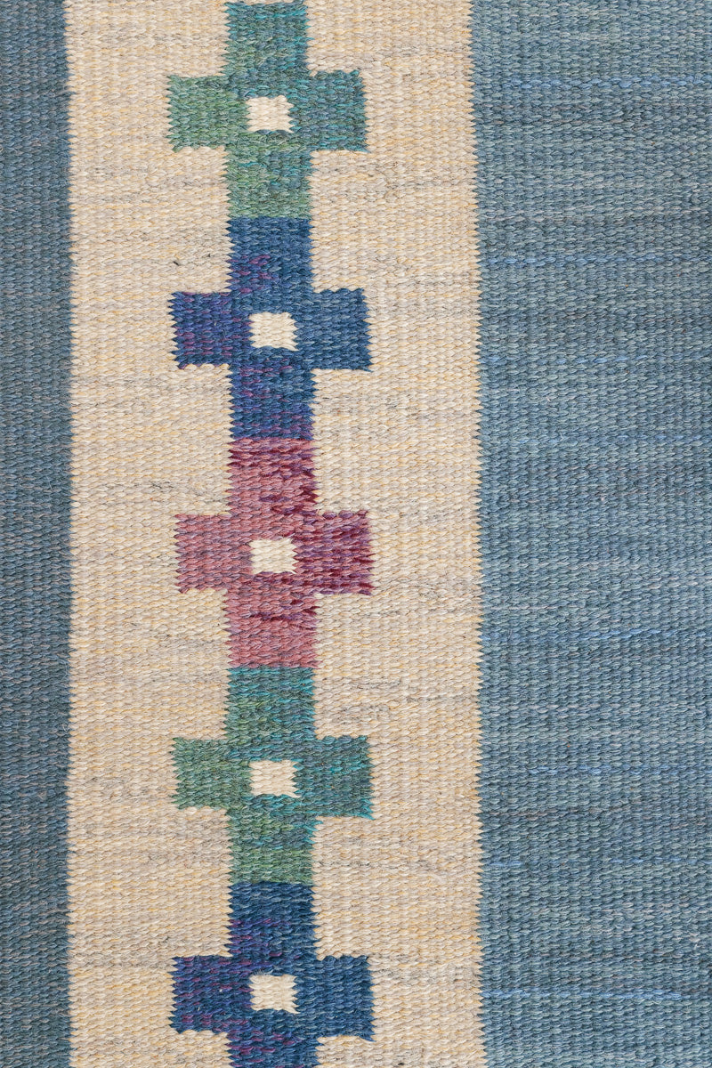 Lumi is a signed vintage Swedish flatweave rug by Anna-Greta Sjöqvist, featuring a calm blue field framed by ivory borders and delicate geometric motifs. Handwoven in wool using the traditional rölakan technique.