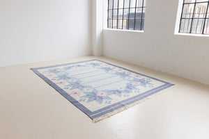 Hallie is an large original röllakan flat weave from the 1960s. This rug shows beautiful tones of blue, featuring bold geometric design with hints of pink within the motifs.