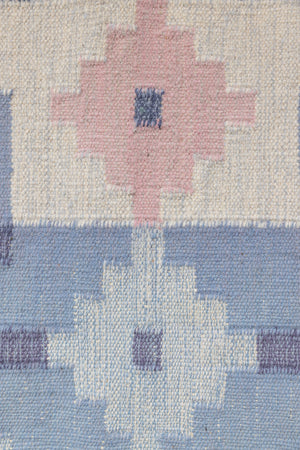 Hallie is an large original röllakan flat weave from the 1960s. This rug shows beautiful tones of blue, featuring bold geometric design with hints of pink within the motifs.