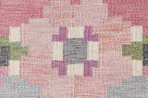 Kara is a vintage Swedish flatweave rug by Ingegerd Silow, featuring a soft pink field, denim blue ground and a pretty and stylised floral border. A leading figure in mid-century Swedish textile design, Silow is known for balancing traditional Nordic craftsmanship with a more decorative, expressive sensibility. This vintage rug features this signature style in its subtle yet playful floral border set against a calm field.