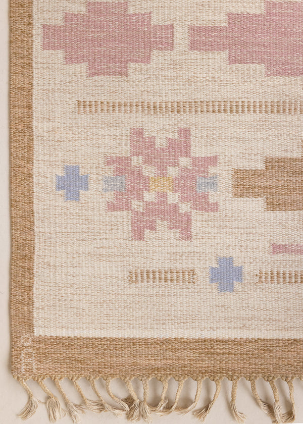 Trina is an original Swedish röllakan rug handwoven by the mid-century textile designer Anna Johanna Angström. This vintage rug features geometric designs in pink, blue, and brown on a beige ground.