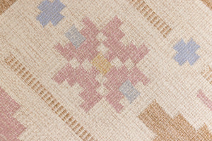 Trina is an original Swedish röllakan rug handwoven by the mid-century textile designer Anna Johanna Angström. This vintage rug features geometric designs in pink, blue, and brown on a beige ground.