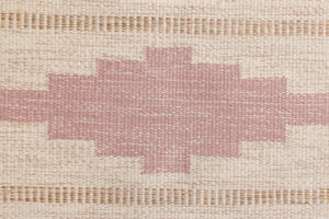 Trina is an original Swedish röllakan rug handwoven by the mid-century textile designer Anna Johanna Angström. This vintage rug features geometric designs in pink, blue, and brown on a beige ground.
