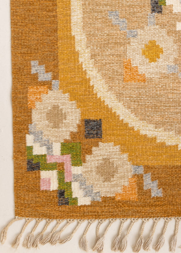 Kaia is a signed vintage Swedish flatweave rug by Ingegerd Silow, featuring a warm ochre field centred framed by stylised florals