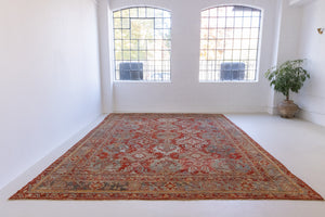 Handwoven antique Oushak carpet with a red field and an intricate decorative design in blue