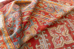 An antique Turkish Oushak rug in rich red with deep blue and ivory