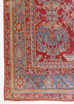 An antique Turkish Oushak rug in rich red with deep blue and ivory