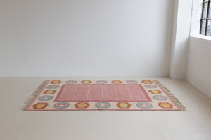 A Vintage Swedish Rug by Ingegerd Silow. An original röllakan flatweave carpet featuring a pink field and unique geometric design. 