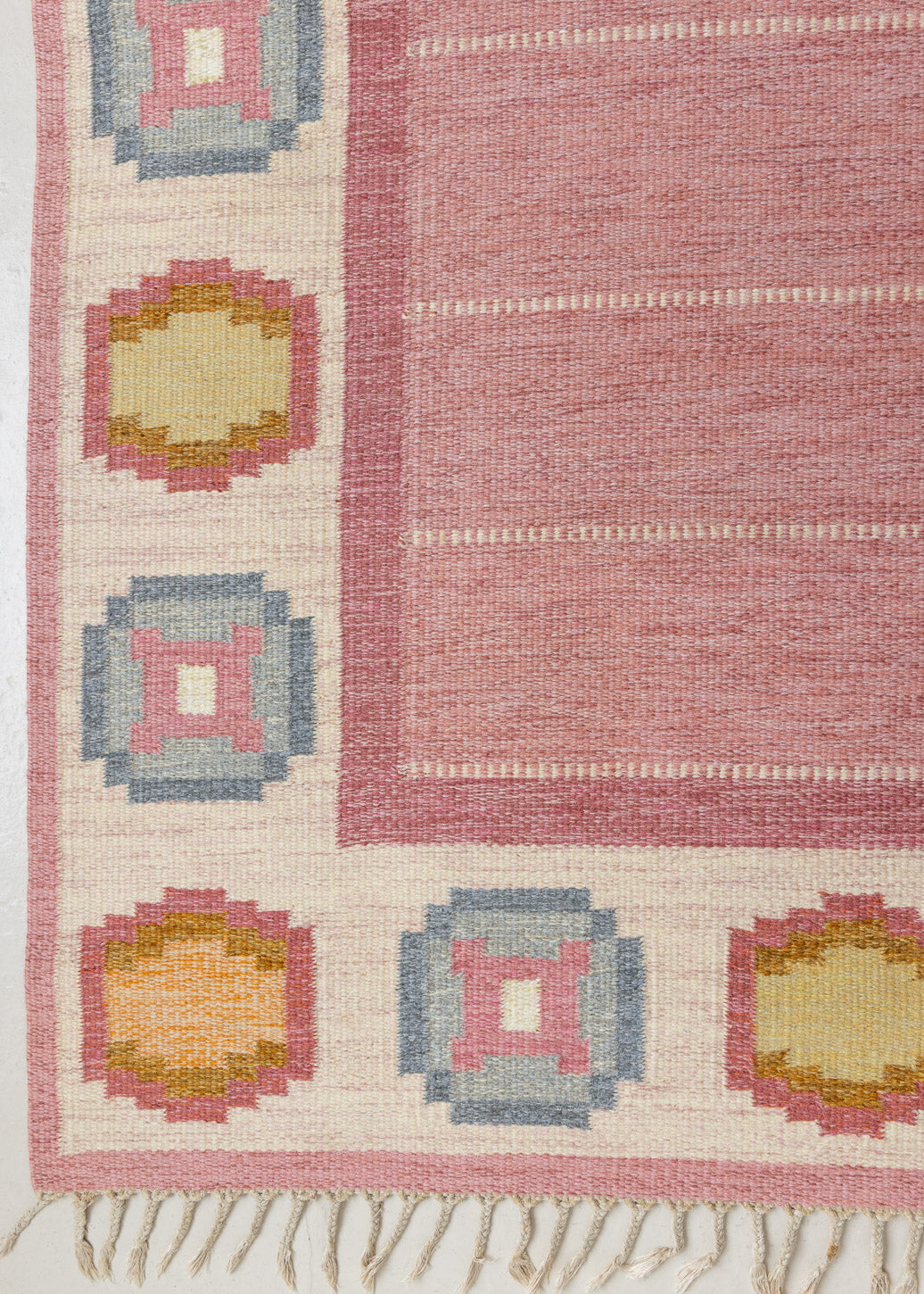 A Vintage Swedish Rug by Ingegerd Silow. An original röllakan flatweave carpet featuring a pink field and unique geometric design. 