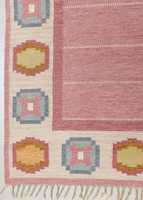 A Vintage Swedish Rug by Ingegerd Silow. An original röllakan flatweave carpet featuring a pink field and unique geometric design. 
