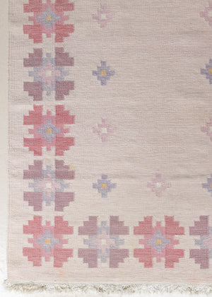 A vintage Swedish flatweave kilim rug with  a pink field and floral design. 
