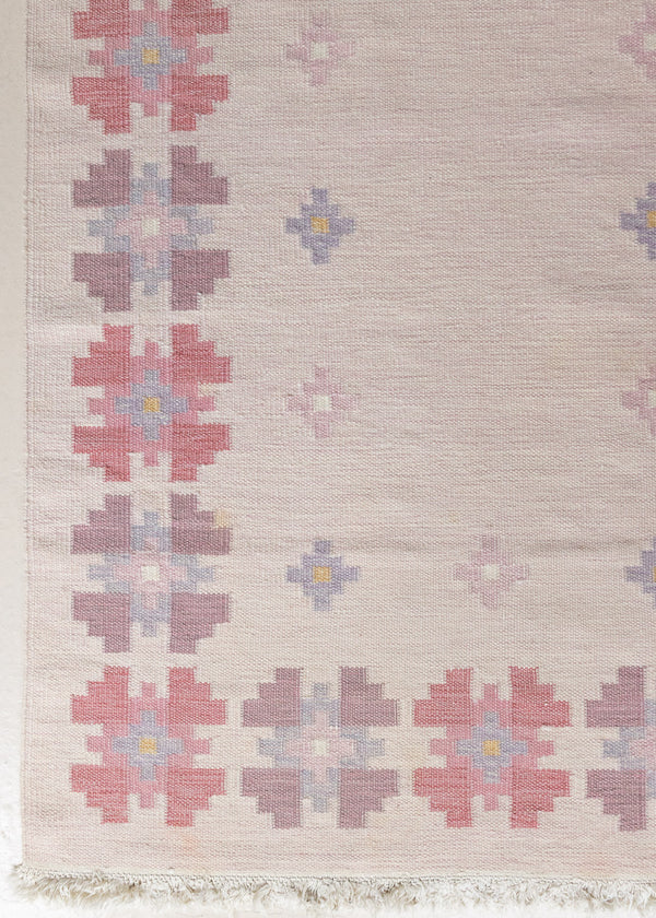 A vintage Swedish flatweave kilim rug with  a pink field and floral design. 