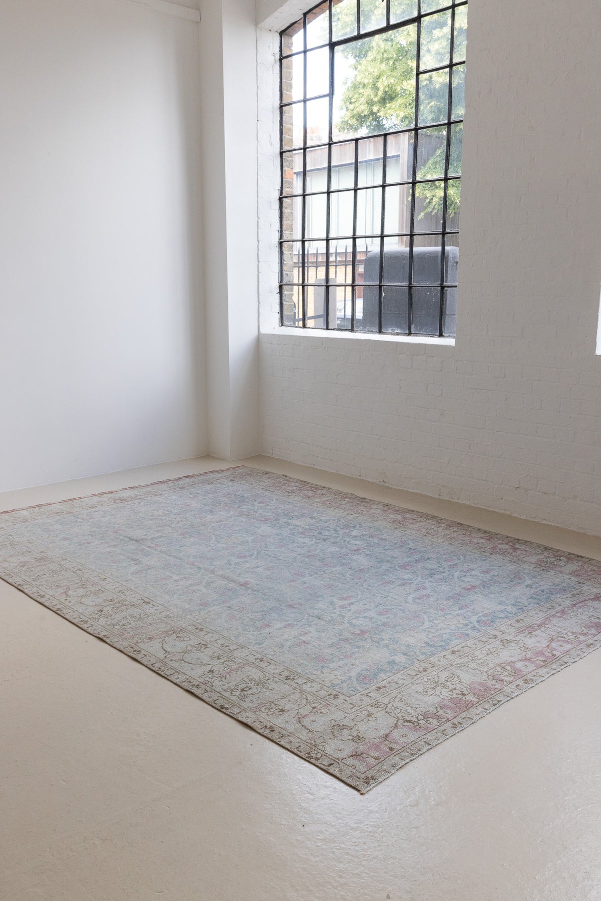This is an antique Persian Tabriz handwoven carpet in muted blue and pinky red with ivory tones. This vintage hand woven wool rug features a all over floral design.