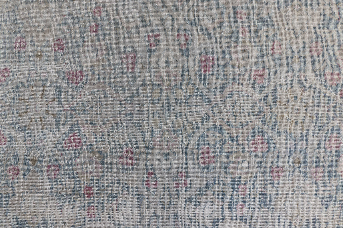 This is an antique Persian Tabriz handwoven carpet in muted blue and pinky red with ivory tones. This vintage hand woven wool rug features a all over floral design.