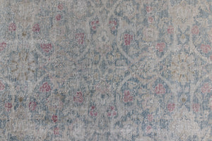This is an antique Persian Tabriz handwoven carpet in muted blue and pinky red with ivory tones. This vintage hand woven wool rug features a all over floral design.
