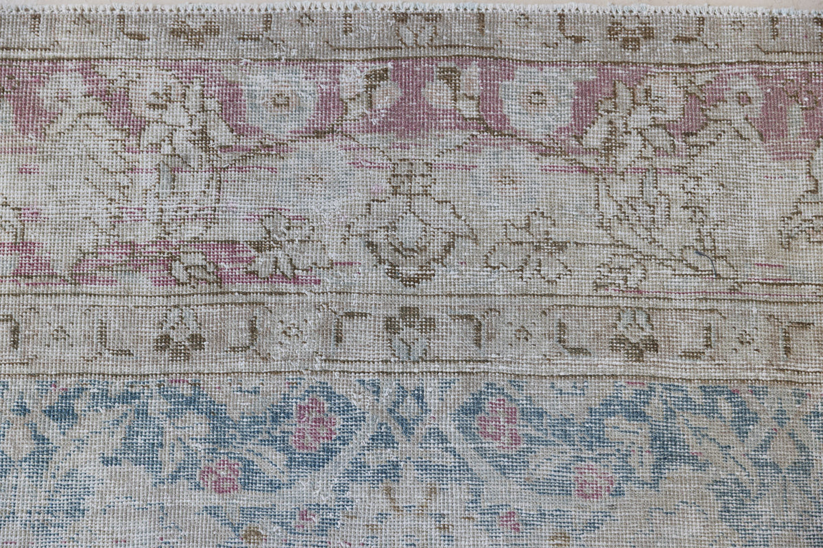 This is an antique Persian Tabriz handwoven carpet in muted blue and pinky red with ivory tones. This vintage hand woven wool rug features a all over floral design.
