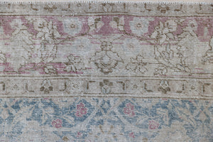 This is an antique Persian Tabriz handwoven carpet in muted blue and pinky red with ivory tones. This vintage hand woven wool rug features a all over floral design.