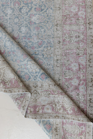 This is an antique Persian Tabriz handwoven carpet in muted blue and pinky red with ivory tones. This vintage hand woven wool rug features a all over floral design.