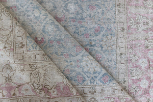 This is an antique Persian Tabriz handwoven carpet in muted blue and pinky red with ivory tones. This vintage hand woven wool rug features a all over floral design.
