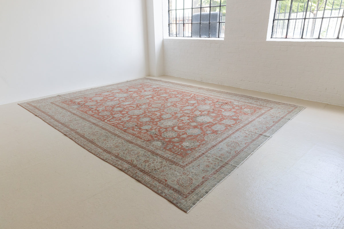 This is an antique Persian Kashan handwoven carpet in blue red and ivory tones. This hand woven wool rug features a all over floral design.