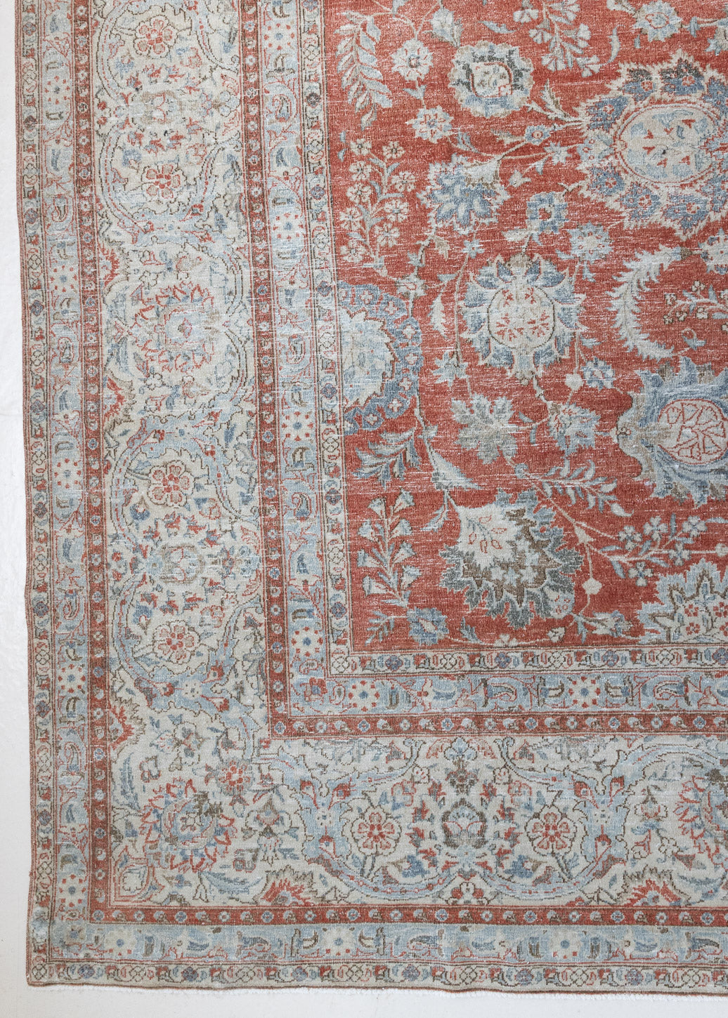 This is an antique Persian Kashan handwoven carpet in blue red and ivory tones. This hand woven wool antique rug features a all over floral design.