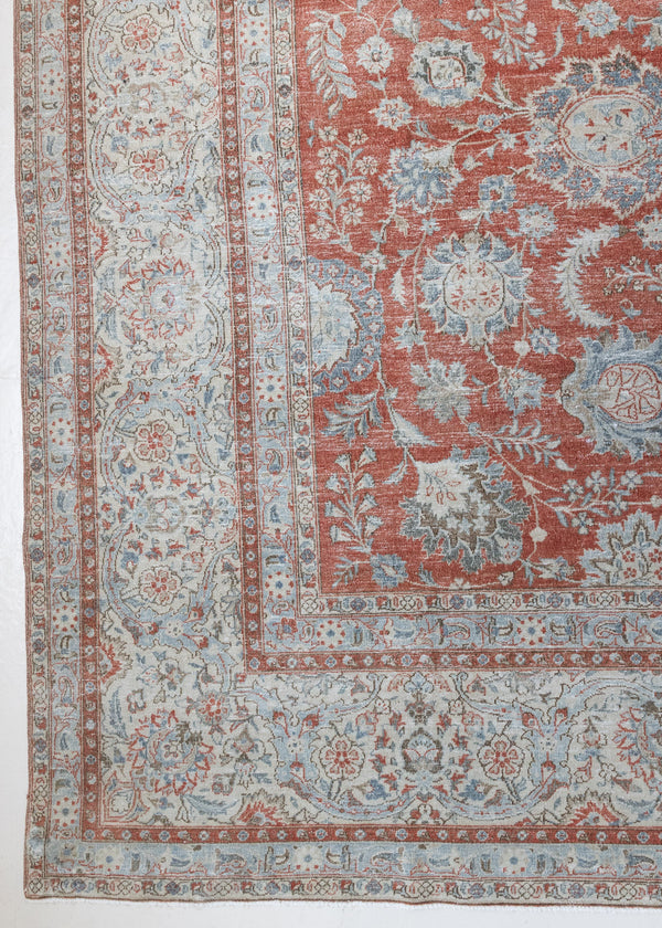 This is an antique Persian Kashan handwoven carpet in blue red and ivory tones. This hand woven wool antique rug features a all over floral design.