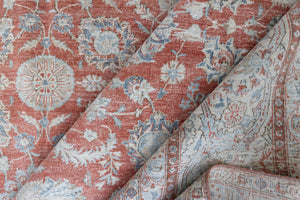 This is an antique Persian Kashan handwoven carpet in blue red and ivory tones. This hand woven antique wool rug features a all over floral design.
