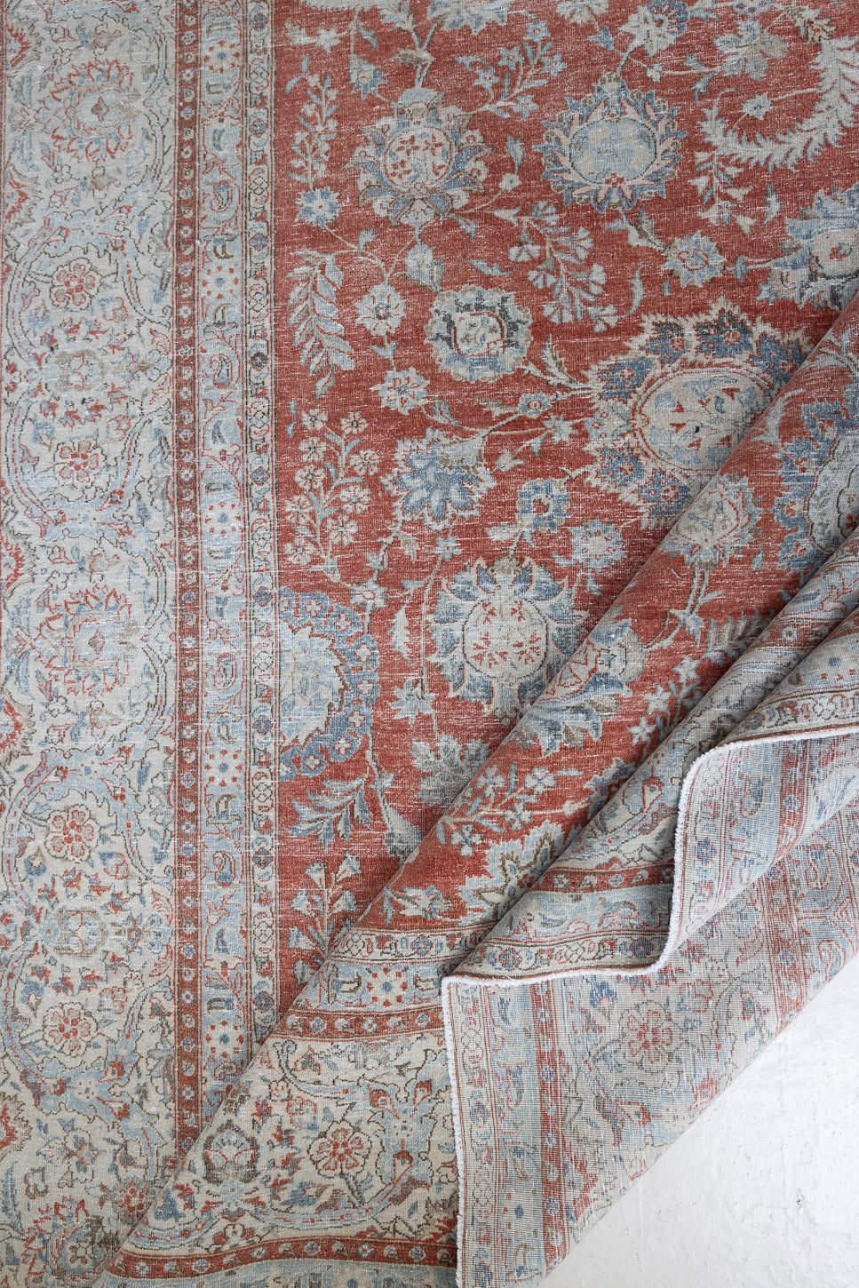 This is an antique Persian Kashan handwoven carpet in blue red and ivory tones. This vintage hand woven wool rug features a all over floral design.