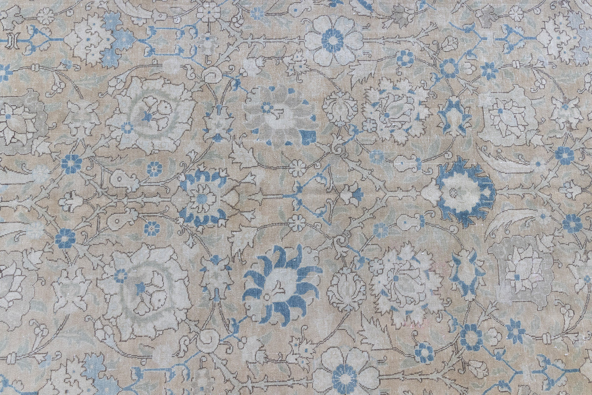 This is an antique Persian Tabriz handwoven carpet in muted blue with ivory tones. This vintage hand woven wool rug features a all over floral design.