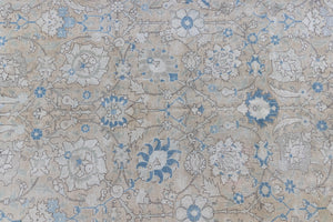 This is an antique Persian Tabriz handwoven carpet in muted blue with ivory tones. This vintage hand woven wool rug features a all over floral design.