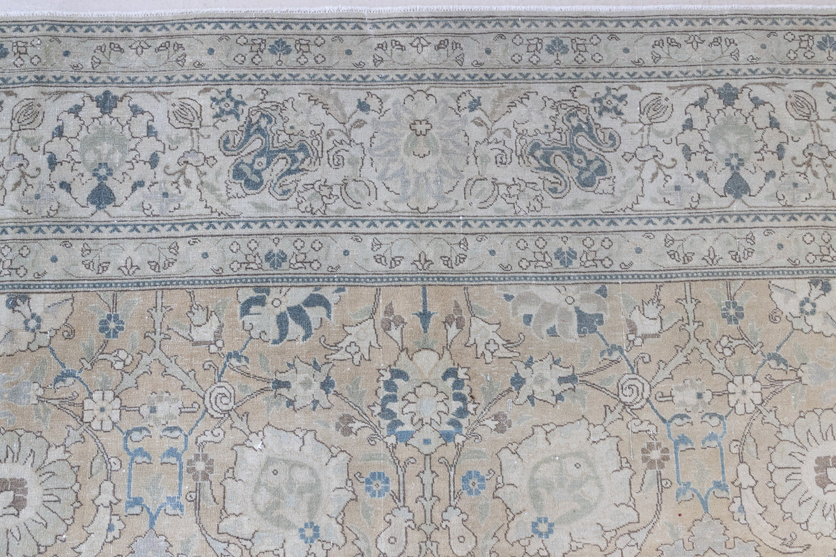 This is an antique Persian Tabriz handwoven carpet in muted blue with ivory tones. This vintage hand woven wool rug features a all over floral design.