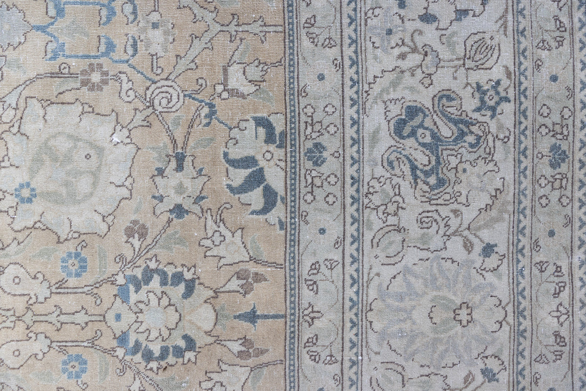 This is an antique Persian Tabriz handwoven carpet in muted blue with ivory tones. This vintage hand woven wool rug features a all over floral design.
