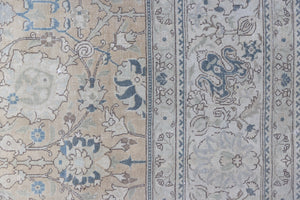 This is an antique Persian Tabriz handwoven carpet in muted blue with ivory tones. This vintage hand woven wool rug features a all over floral design.