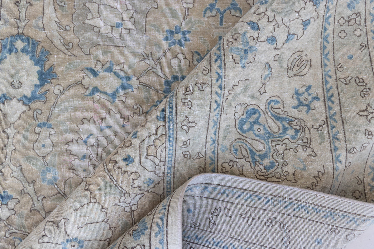 This is an antique Persian Tabriz handwoven carpet in muted blue with ivory tones. This vintage hand woven wool rug features a all over floral design.